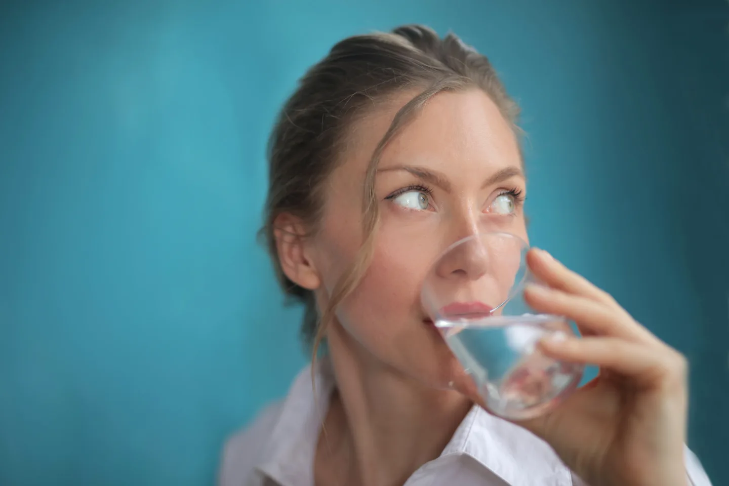 Frau trinkt Wasser aus einem Glas.